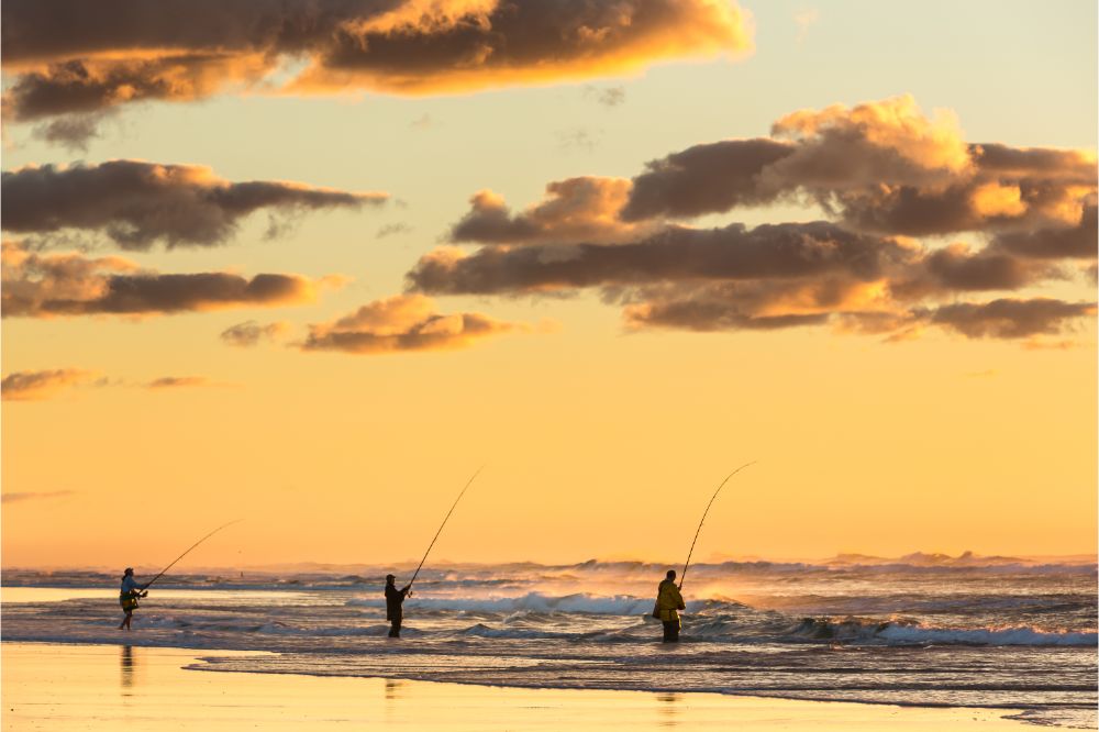three person surf fishing at sunrise