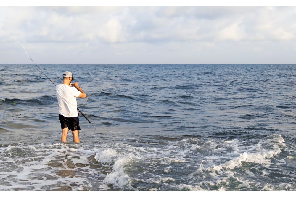 Fisherman standing at the seashore hooks a fish