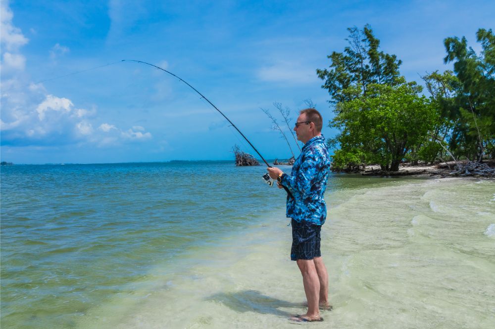 Caucasian man 60 years old with a fishing rod in his hands while fishing on the beach
