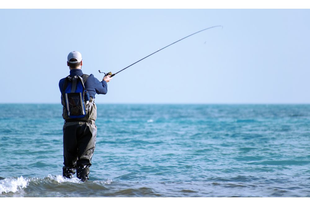 Fisherman standing at the seashore hooks a fish
