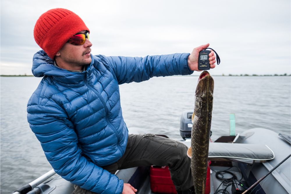 Young amateur angler with pike fish