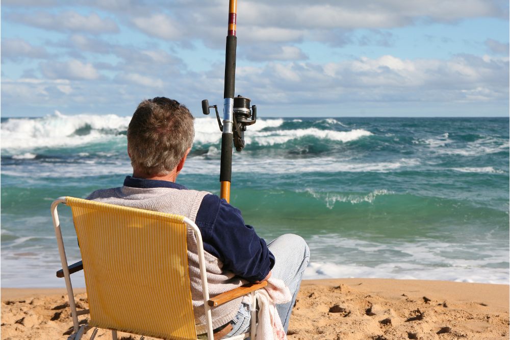 man sitting at shore fishing