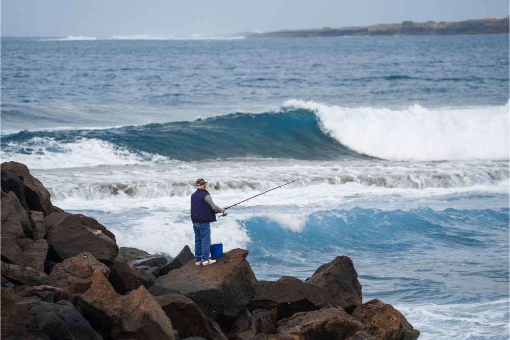 Fisherman on the rocks with rough sea