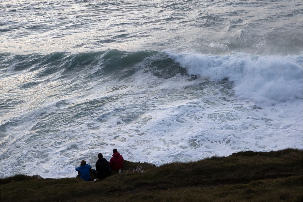  friends watch as waves crash in from Atlantic