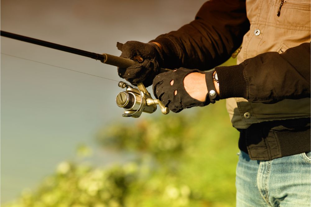 fisherman wearing fishing gloves and holding the fishing rod