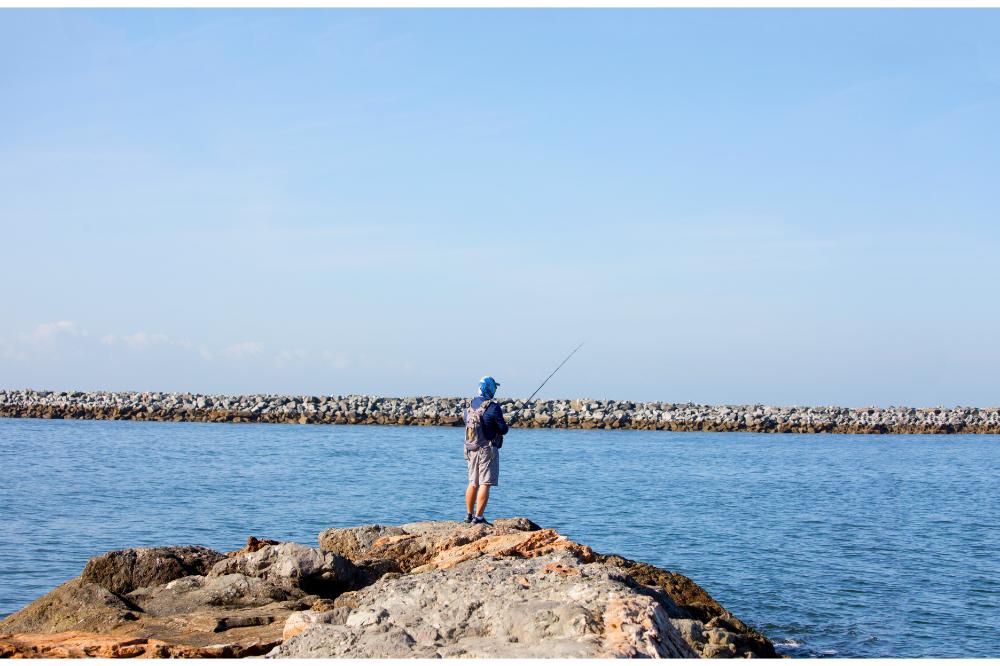 Man fishing off the pier at Corona Del Mar, Newport Beach, California